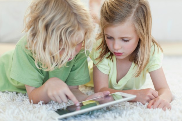 Siblings together on the floor using tablet